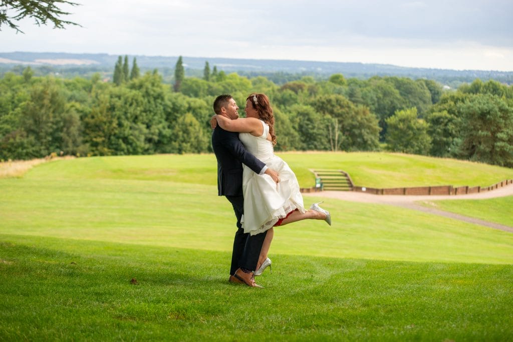 married couple hugging and smiling at each other on a fairway at a wedding venue in woking