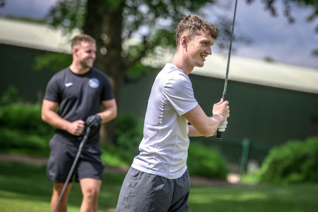golfer watching ball smiling at a golf course in woking