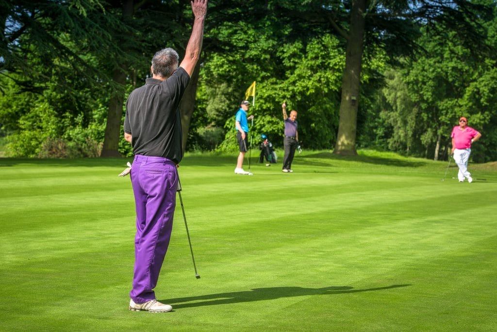 Man celebrating after making a putt on the green at a golf course in Surrey