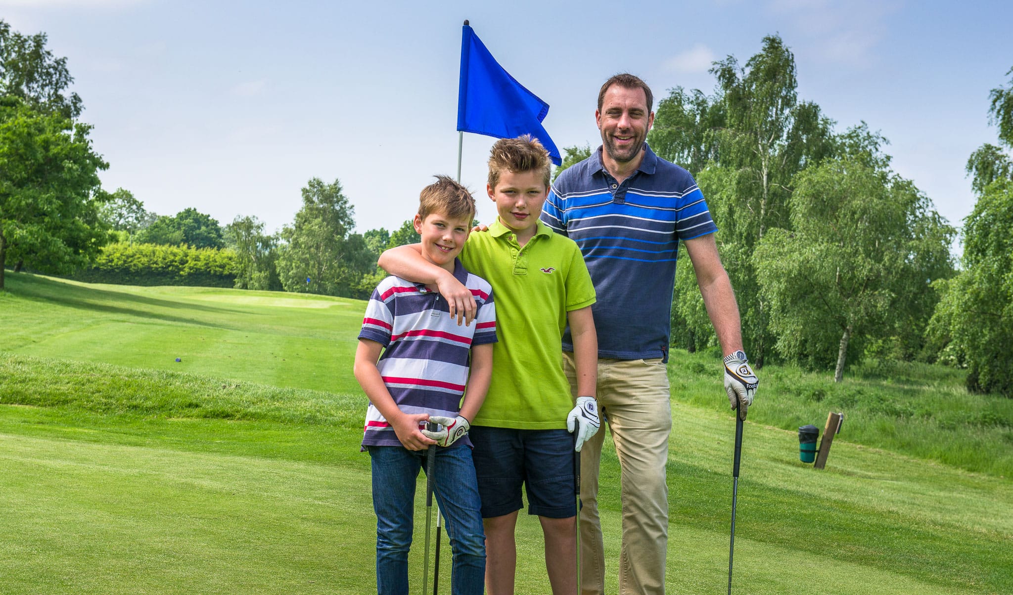dad and his two boys smiling on the par 3 course in woking