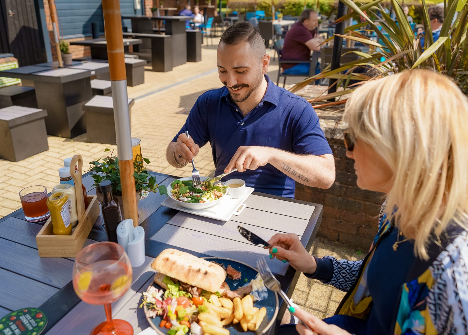 man smiling with wife enjoying a vibrant salad on the terrace at an outdoor restaurant in woking