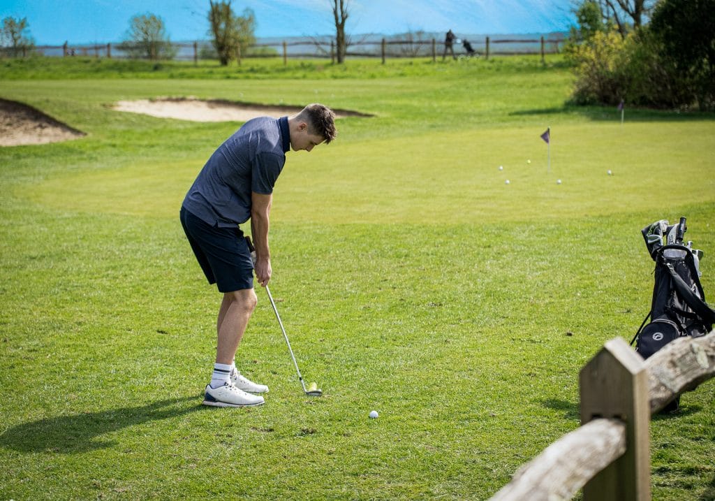 Golfer chipping on a practice green at a golf club in woking