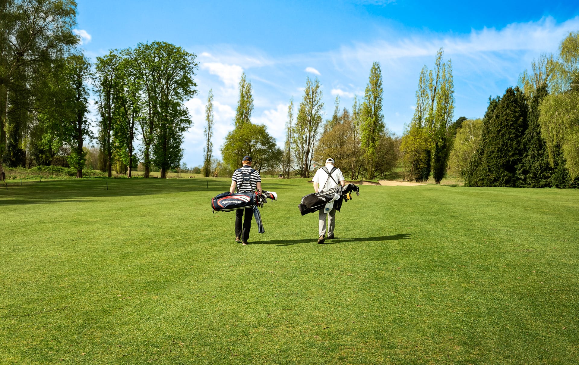 Two golfers walking towards the hole on a golf course in Surrey