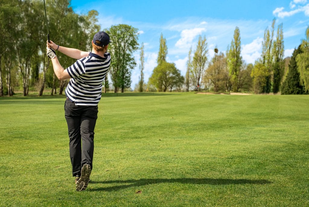 Man holding golf club after hitting a ball at a golf course in Woking