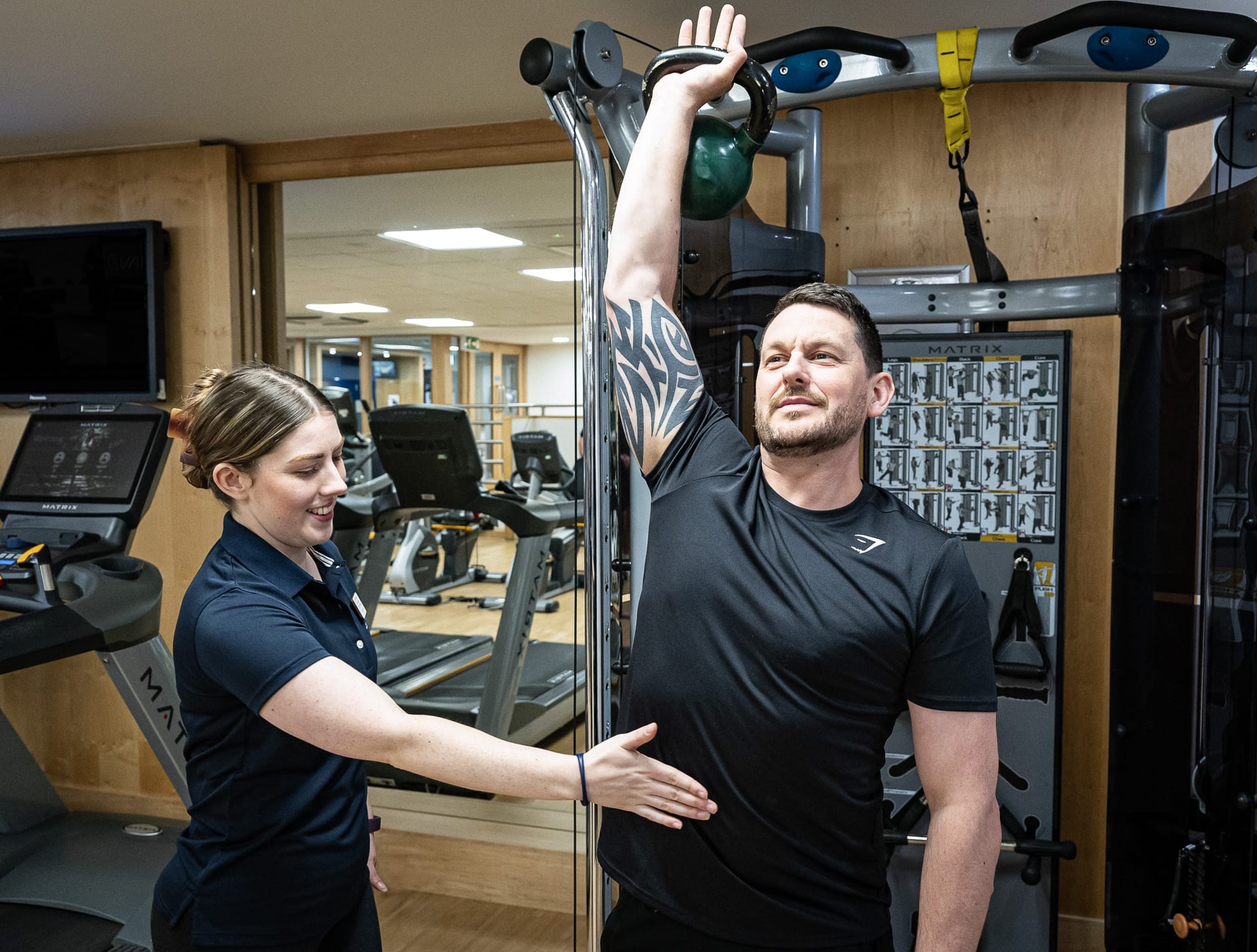 One-on-one personal training session in health club in Woking with trainer supporting client